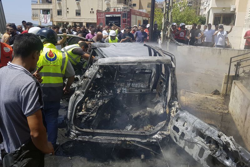 Civil Defense workers inspect the remains of a burned car that was hit by an Israeli strike in the southern port city of Sidon, Lebanon, Monday, Aug. 26, 2024. (AP Photo/Mohammed Zaatari)