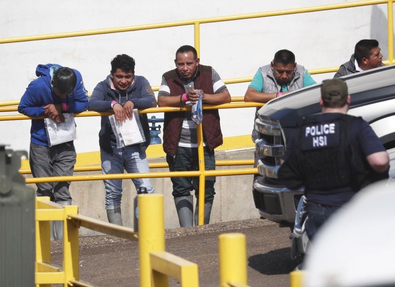 Handcuffed workers await transportation to a processing center following a raid by U.S. immigration officials at a Koch Foods Inc. plant in Morton, Miss. U.S. immigration officials raided several Mississippi food processing plants in early August and signaled that the early-morning strikes were part of a large-scale operation targeting owners as well as employees. AP PHOTO / ROGELIO V. SOLIS