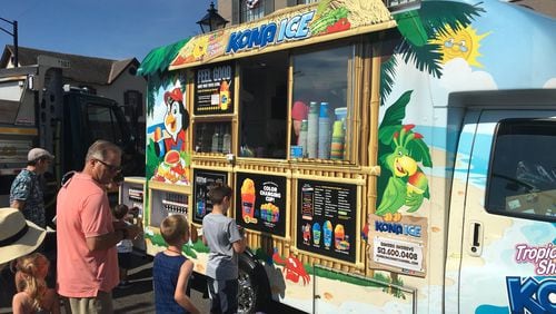 Customers line up at a Kona Ice truck at Centerville’s annual Americana Festival. Owner Sandra Andrews said the high temperatures meant the truck would sell a lot of shaved ice at the festival this year.