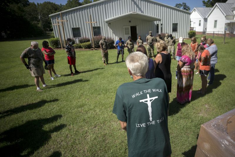 SUMMERTOWN, GA - JULY 14, 2020: Summertown Food Pantry volunteer Paul Pierre leads a group in prayer, blessing the food they are about to give to the 116 people lined up in their cars. (AJC Photo/Stephen B. Morton)