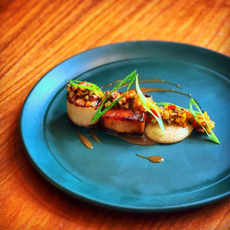 A grilled scallop is paired with a bit of peach-glazed pork belly that has been steamed, smoked and finished on the grill at Nàdair. (Courtesy of Kevin Gillespie)