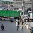 People try to cross through shipping containers set up by authorities to prevent supporters of imprisoned former Prime Minister Imran Khan from holding a rally to demand his release in Lahore, Pakistan, Saturday, Oct. 5, 2024. (AP Photo/K.M. Chaudary)