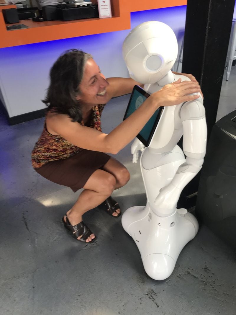 “I was so enamored with little Pepper the host that I felt the urge to hug it,” writes AJC dining editor Ligaya Figueras, seen with the robot employed at Big Bang Pizza in Brookhaven. CONTRIBUTED BY TYSON A. HORNE