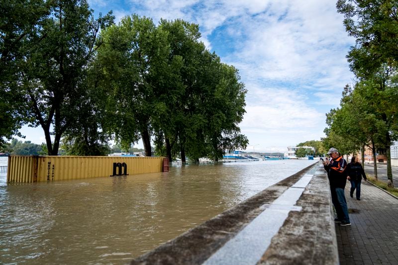 People take photos of rising waters on the banks of the River Danube, in Bratislava, Slovakia, Tuesday, Sept. 17, 2024. (AP Photo/Tomas Hrivnak)