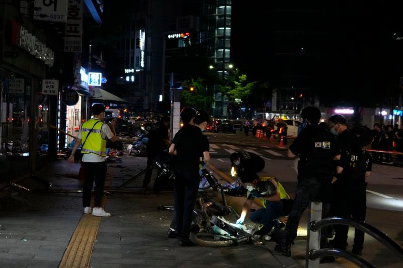Police officers investigate a car accident scene near Seoul City Hall in downtown Seoul, South Korea, Tuesday, July 2, 2024. A car hit pedestrians waiting at a traffic light in central Seoul on Monday evening, killing nine people and injuring four, South Korea's emergency officials said. (AP Photo/Ahn Young-joon)