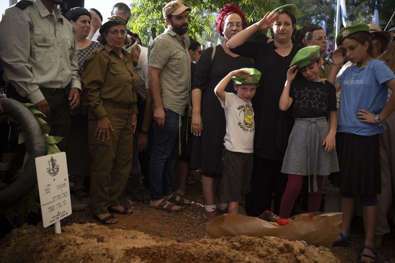 The wife and children salute as they mourn at the grave of reservist Staff Sergeant Rafael Kauders during his funeral at a cemetery in the West Bank settlement of Kfar Etzion, Thursday, June 6, 2024. Kauders, 39, was killed during a drone attack launched by the Lebanese militant group Hezbollah toward a gathering of military officials at a village in northern Israel.(AP Photo/Leo Correa)