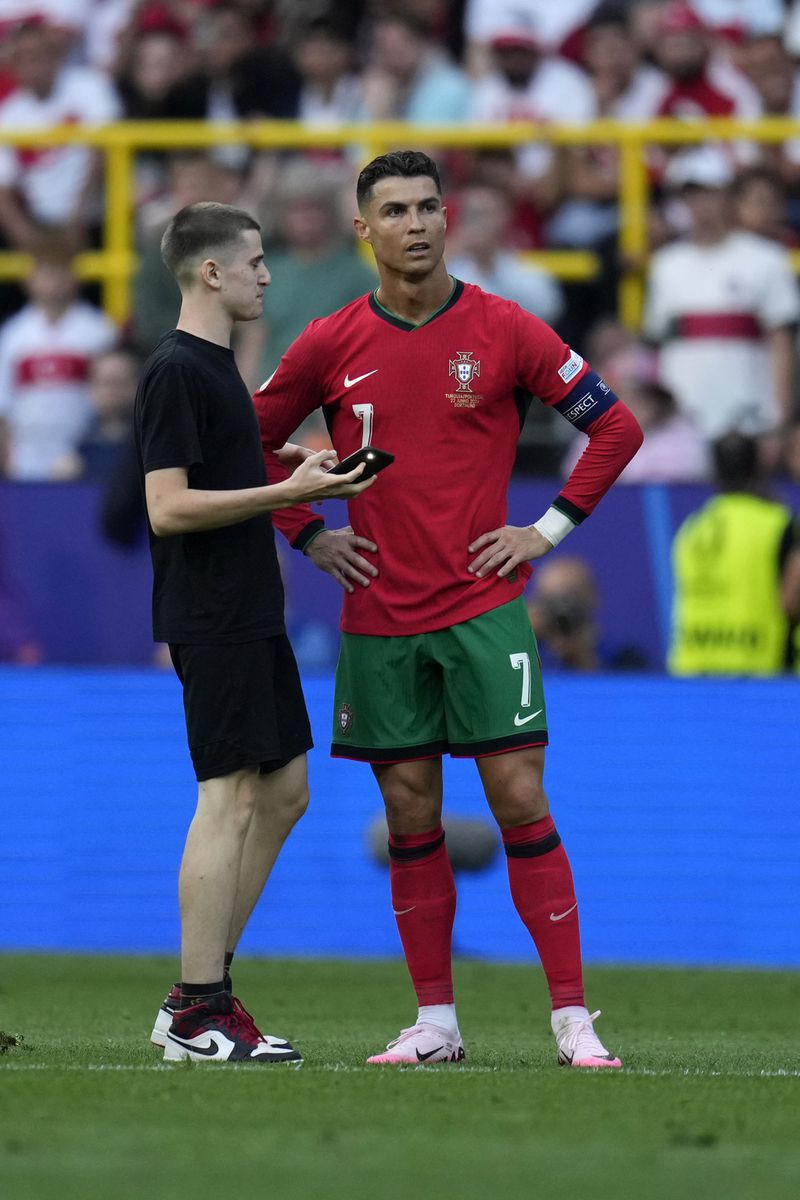 A pitch invader stands next to Portugal's Cristiano Ronaldo during a Group F match between Turkey and Portugal at the Euro 2024 soccer tournament in Dortmund, Germany, Saturday, June 22, 2024. (AP Photo/Themba Hadebe)