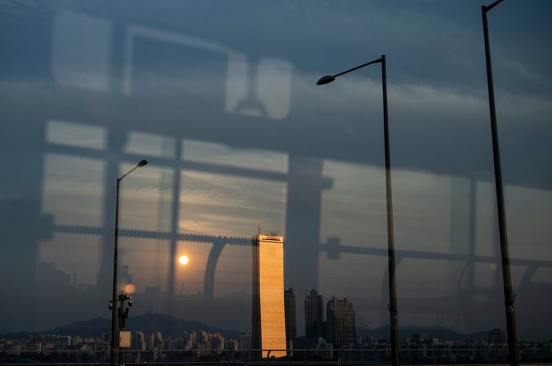 The 63 Building, once the tallest skyscraper in Asia, stands by the Han River, reflecting the light of the setting sun in Seoul, Wednesday, May 22, 2024. (AP Photo/Jae C. Hong)