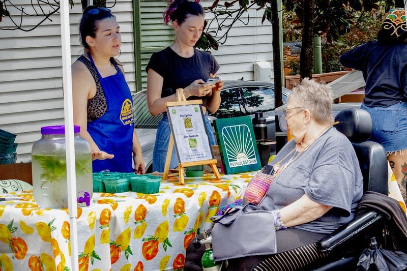 Reynoldstown Farmers Market committee member Clara Camber talks about black-eyed peas with shopper Jean Kozelka at the 2023 farmers market booth selling full-price and half-price produce from Grier Farms. (Courtesy of Keye Bodison)