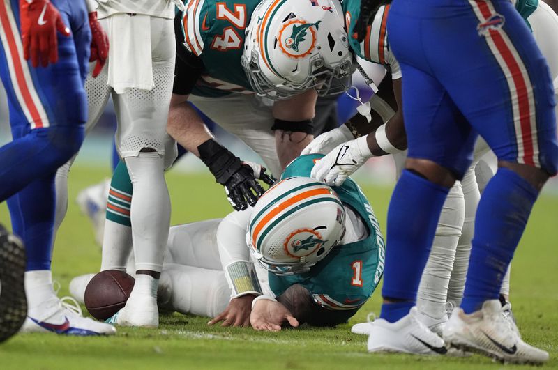 Miami Dolphins quarterback Tua Tagovailoa (1) is assisted on the field during the second half of an NFL football game against the Buffalo Bills, Thursday, Sept. 12, 2024, in Miami Gardens, Fla. (AP Photo/Rebecca Blackwell)