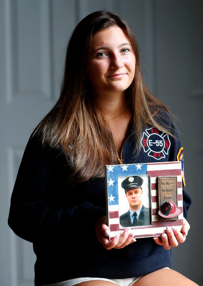 Capri Yarosz holds a photo of New York firefighter Christopher Michael Mozzillo, Saturday, Sept. 7, 2024, in Freehold, N.J.. Mozzillo, who died in the 9/11 attacks, was Yarosz's uncle. (AP Photo/Noah K. Murray)