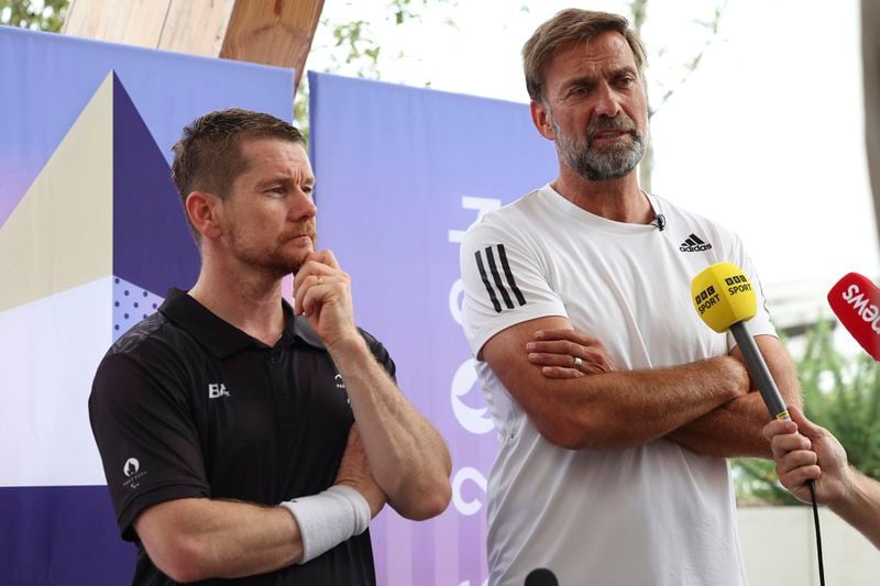 German football manager Jurgen Klopp, right, and para badminton player Wojtek Czyz discuss the results of Czyz's match in Porte La Chapelle Arena during the Paralympic Games on Wednesday, Aug. 28, 2024, in Paris. (AP Photo/Samantha Hurley).