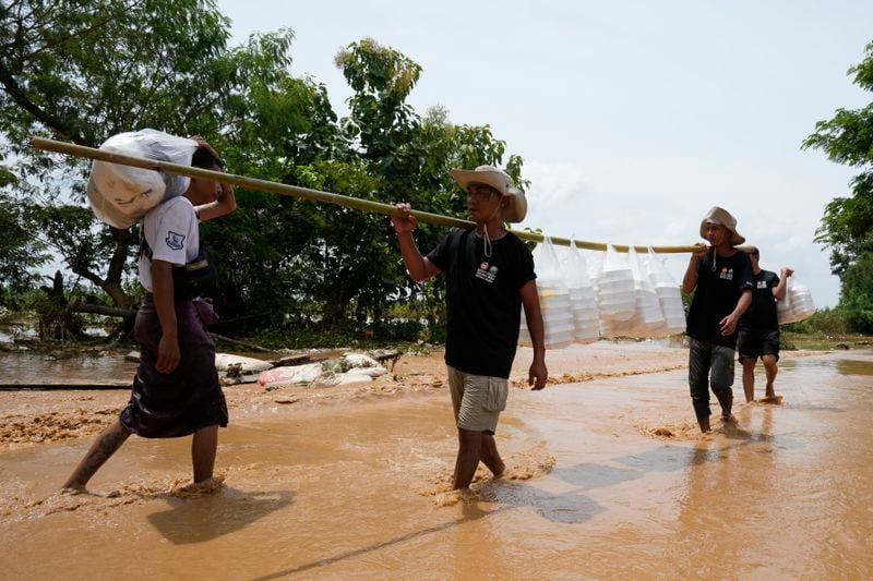 Local residents carrying foods wade through a flooded road in Naypyitaw, Myanmar, Saturday, Sept. 14, 2024. (AP Photo/Aung Shine Oo)