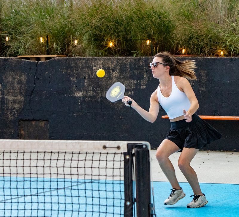 Pickleball is played with a paddle rather than a racket, and with a smaller, harder ball. The game doesn't require as much running back and forth as tennis, and players — both teammates and opponents — are physically closer to each other. (Jenni Girtman for The Atlanta Journal-Constitution)