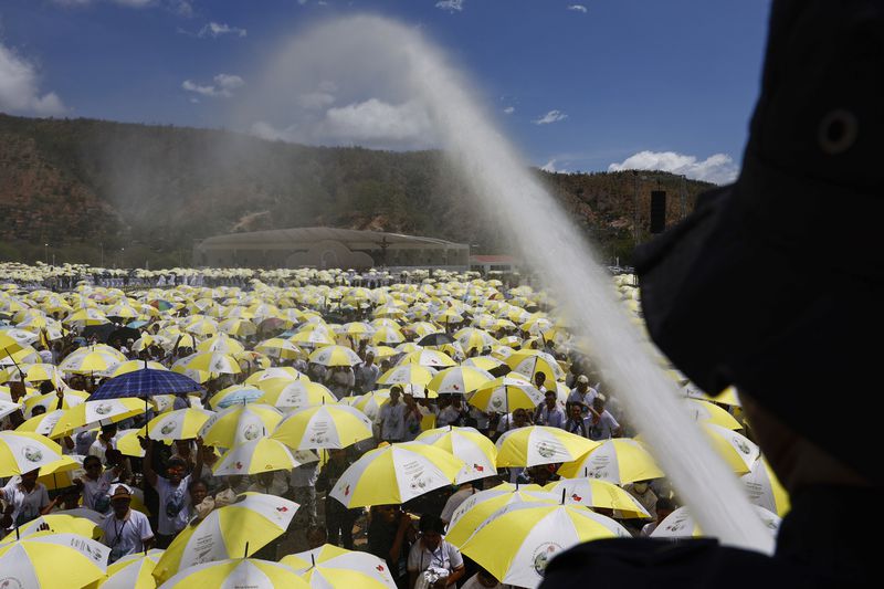 A firefighter sprays water on Catholic faithful gathered for a Holy Mass with Pope Francis at the Esplanade of Taci Tolu in Dili, East Timor, Tuesday, Sept.10, 2024. (Willy Kurniawan/Pool Photo via AP)