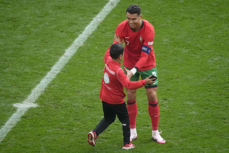 A young pitch invader runs to Portugal's Cristiano Ronaldo during a Group F match between Turkey and Portugal at the Euro 2024 soccer tournament in Dortmund, Germany, Saturday, June 22, 2024. (AP Photo/Michael Probst)