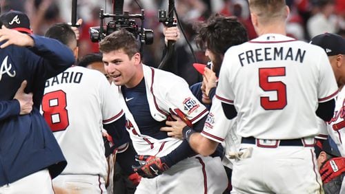 Braves third baseman Austin Riley (center) celebrates with teammates after hitting a walk-off single that scored second baseman Ozzie Albies in 3-2 win of Game 1 of the NLCS against the Los Angeles Dodgers Saturday, Oct. 16, 2021,  at Truist Park in Atlanta. (Hyosub Shin / Hyosub.Shin@ajc.com)