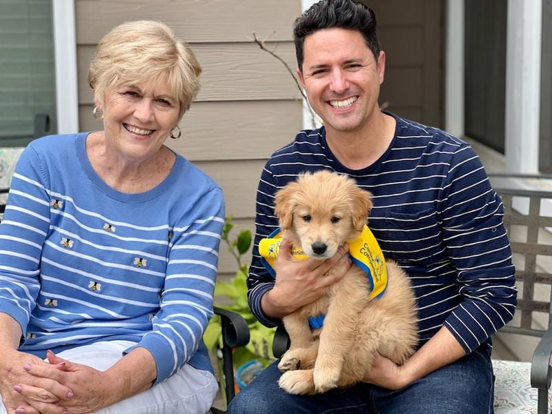 Tally is the 20th puppy that Cecilia Kurland and her daughter, Abigail Whitlock, will have raised and trained to be a future service dog. “At age 11 Abigail wanted a puppy. This was a way for my daughter to have a puppy but to also do something for others,” said Kurland. (Pictured L-R: Cecilia Kurland, Patric Raburn with Tally in his lap).