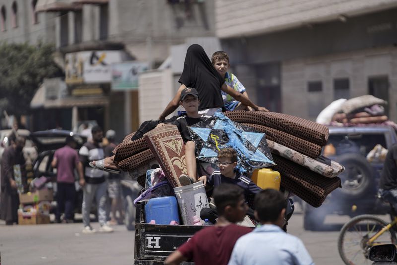 Palestinians evacuate a school that had been their shelter, in eastern Deir al-Balah, Gaza Strip, Friday, Aug. 16, 2024, after the Israeli military dropped leaflets asking civilians to evacuate from the area, saying forces plan to respond to rocket fire that targeted Israel. (AP Photo/Abdel Kareem Hana)