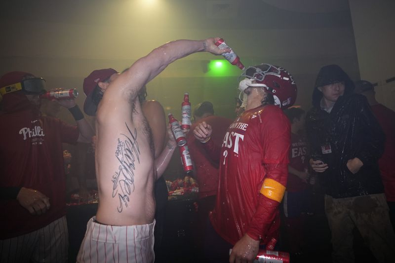 Philadelphia Phillies' Bryson Stott, right, and Bryce Harper celebrate after the Phillies won a baseball game against the Chicago Cubs to clinch the NL East title, Monday, Sept. 23, 2024, in Philadelphia. (AP Photo/Matt Slocum)