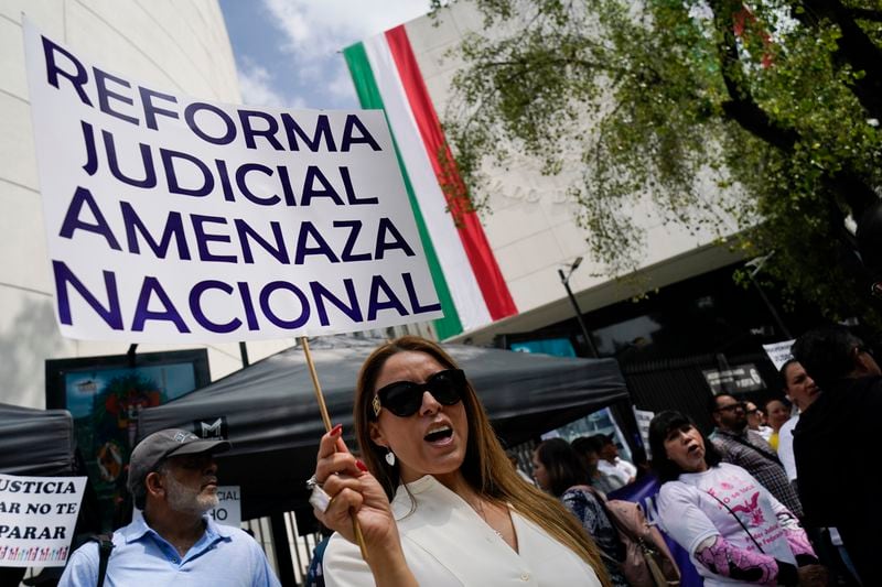 A demonstrator holds the sign "Judicial reform national threat" during a protest outside the Senate against a judicial reform bill in Mexico City, Thursday, Sept. 5, 2024, the day after Congress passed legislation that would require all judges to stand for election. (AP Photo/Felix Marquez)