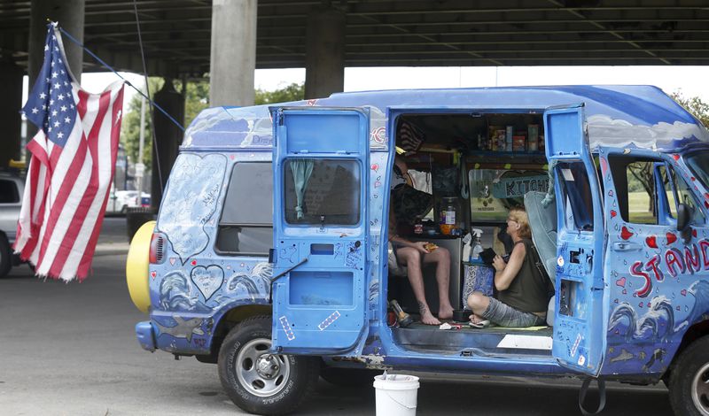 David Walker and Lisa Lampe park their van down by the river and under 64 to remain cool in the heat, Tuesday, June 18, 2024, in Louisville, Ky. (Scott Utterback/Courier Journal via AP)