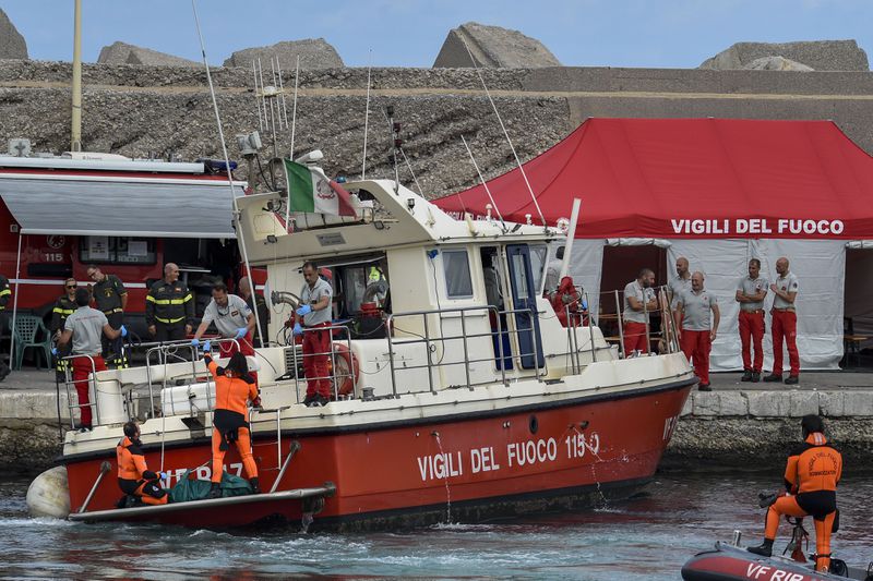 Italian firefighter divers bring ashore in a green bag the body of one of the victims of the UK flag vessel Bayesian, Wednesday, Aug. 21, 2024. The luxury sail yacht was hit by a violent sudden storm and sunk early Monday, while at anchor off the Sicilian village of Porticello near Palermo, in southern Italy. (AP Photo/Salvatore Cavalli)