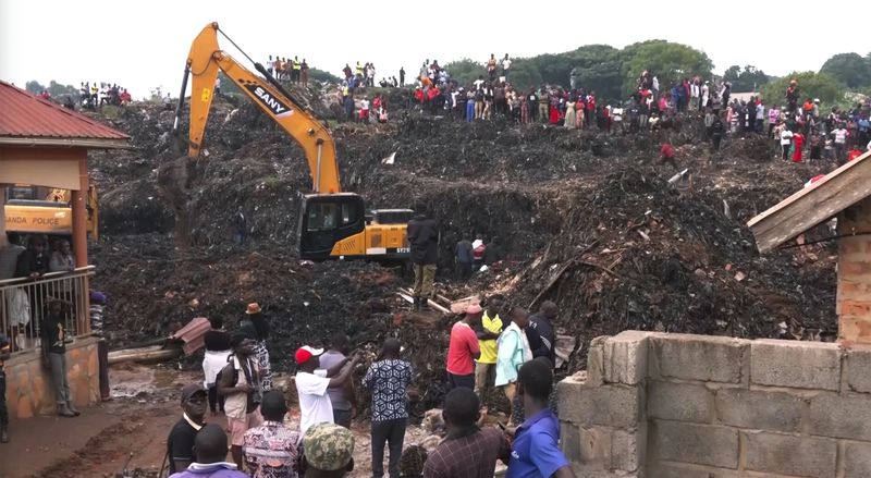 In this photo taken from video people an excavator works at a site of a collapsed landfill in Kampala, Uganda, Saturday, Aug. 10, 2024. At least 18 people were killed after a landfill collapsed late Friday in the Ugandan capital, according to the Red Cross. (AP video via AP)