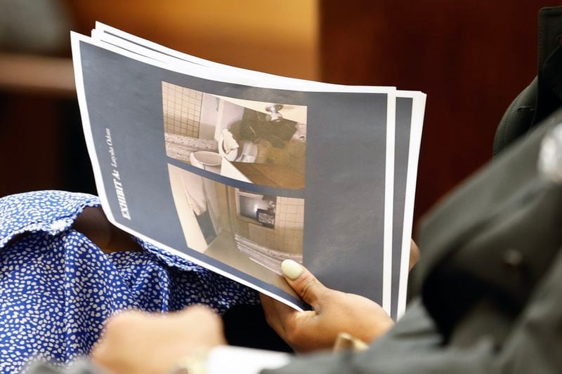 An attendee of the U.S. Senate Human Rights Subcommittee Hearing addressing unsuitable housing conditions holds photo evidence at Roswell City Hall on Monday, March 4, 2024. (Natrice Miller/ Natrice.miller@ajc.com)