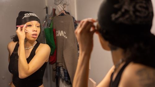 Atlanta rapper Anycia puts on makeup in her bedroom at her family’s home in metro Atlanta in June. (Arvin Temkar / AJC)