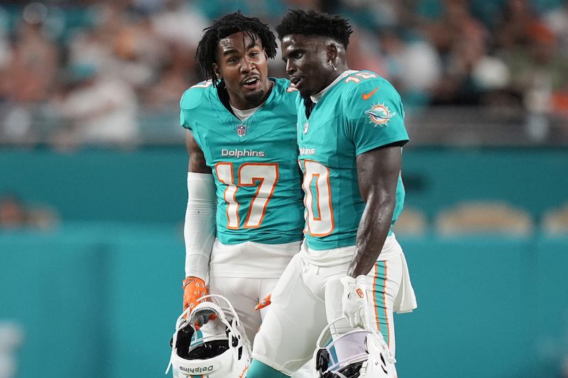 Miami Dolphins wide receiver Jaylen Waddle (17) talks to wide receiver Tyreek Hill (10) during the first half of an NFL football game against the Tennessee Titans, Monday, Sept. 30, 2024, in Miami Gardens, Fla. (AP Photo/Rebecca Blackwell)