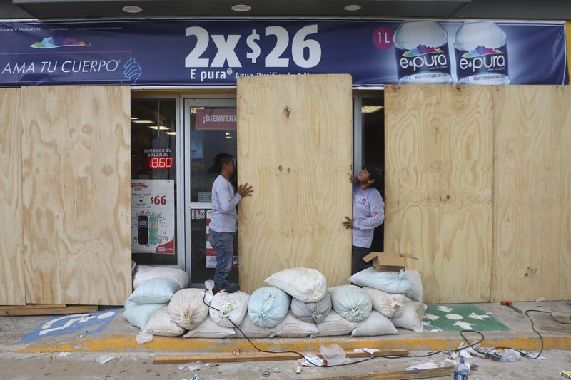 Workers board up a grocery store to protect it from Hurricane Milton, in Progreso, Yucatan state, Mexico, Monday, Oct. 7, 2024. (AP Photo/Martin Zetina)