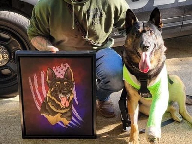 Austell Police Officer Edward Reeves and K9 Jerry Lee show a painting in honor of K9 Jerry Lee done by Smooth Fox Illustration. K9 Jerry Lee had his left leg amputated after being shot by a wanted felon. (Courtesy of Austell Police Department)