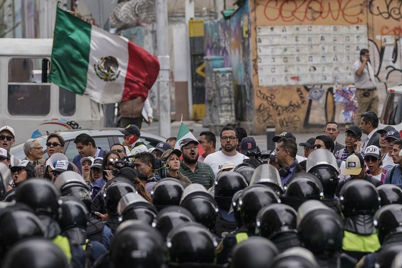 Demonstrators opposing judicial reform that would require all judges to stand for election, protest outside an alternate headquarters for senators who are discussing the reform one day after Mexico's lower house approved it, in Mexico City, Thursday, Sept. 5, 2024, (AP Photo/Felix Marquez)