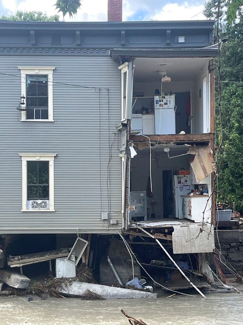 Water flows past a house with a missing wall after severe flooding, Thursday, July 11, 2024, in Plainfield, Vt. (AP Photo/Lisa Rathke)