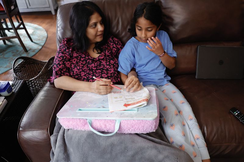 Sowmya Siragowni helps her daughter Anika, 8, with homework at their home in Alpharetta on Wednesday, Oct. 25, 2023. Siragowni, a hospitalist at Emory Saint Joseph’s hospital, was diagnosed with stage 4 ovarian cancer five years ago. (Natrice Miller/ Natrice.miller@ajc.com)
