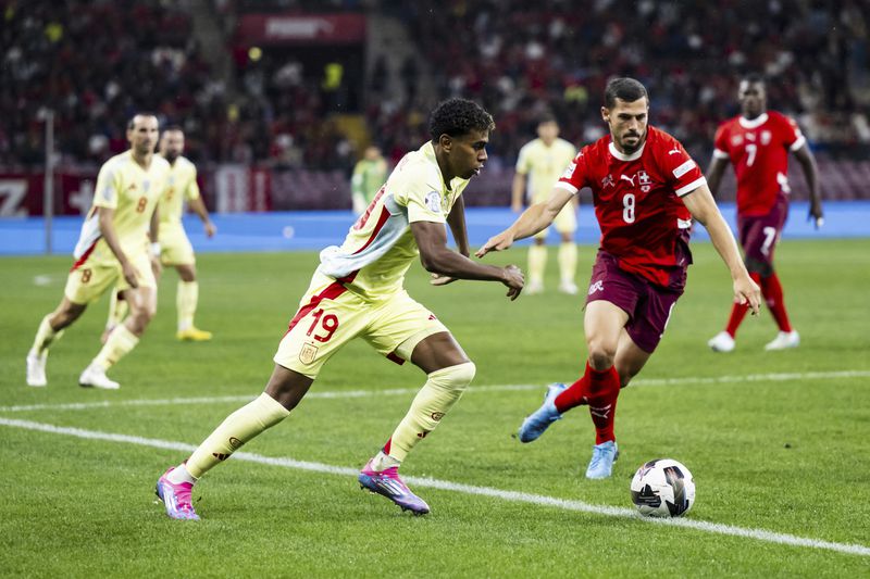 Spain's forward Lamine Yamal, left, fights for the ball with Switzerland's midfielder Remo Freuler, right, during the Nations League group A4 qualifying soccer match between Switzerland and Spain, at the Stade de Geneve, in Geneva, Sunday, Sept. 8, 2024. (Jean-Christophe Bott/Keystone via AP)