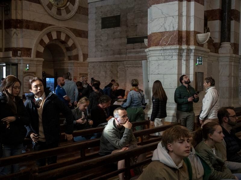 People visit the Notre Dame de la Garde Basilica in Marseille, southern France, Friday, April 19, 2024. (AP Photo/Daniel Cole)