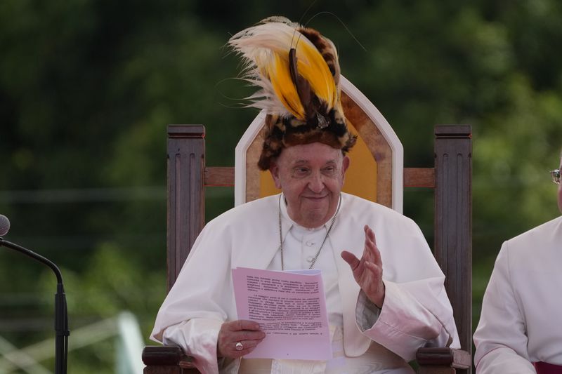 Pope Francis wears a traditional hat during a meeting with faithful in Vanimo, Papua New Guinea, Sunday, Sept. 8, 2024. Despite the considerable security concerns of entering a region torn by tribal rivalries, Francis seemed to relish the jungle visit, perhaps because he felt so much at home. A dozen Argentine missionary priests and nuns have lived in Vanimo with the local community for years and had invited him to come. (AP Photo/Gregorio Borgia)