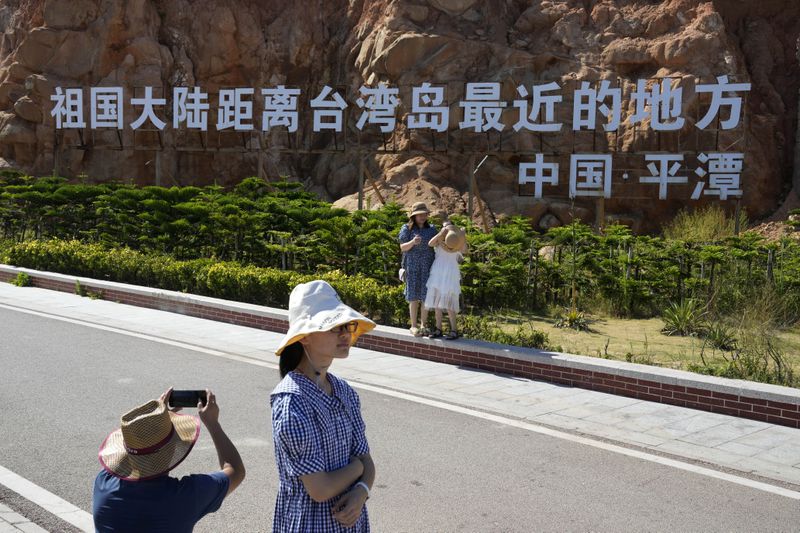 FILE - Tourists pose for photos near a sign that reads "The closest point to Taiwan island from the motherland China, Pingtan" at the 68-nautical-mile scenic spot in Pingtan in southeastern China's Fujian Province, Friday, Aug. 5, 2022. A suspected Chinese state-sponsored hacking group have predominantly stepped up its targeting of Taiwanese organizations, particularly those in sectors such as government, education, technology and diplomacy, according to cybersecurity intelligence company Recorded Future. (AP Photo/Ng Han Guan, File)