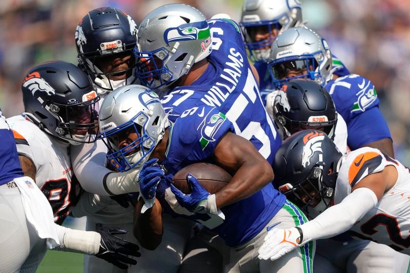 Seattle Seahawks running back Kenneth Walker III (9) is tackled by Denver Broncos players during the first half of an NFL football game Sunday, Sept. 8, 2024, in Seattle. (AP Photo/Lindsey Wasson)