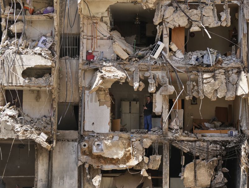 A man watches rescuers sift through the rubble as they search for people still missing at the site of Friday's Israeli strike in Beirut's southern suburbs, Monday, Sept. 23, 2024. (AP Photo/Hassan Ammar)