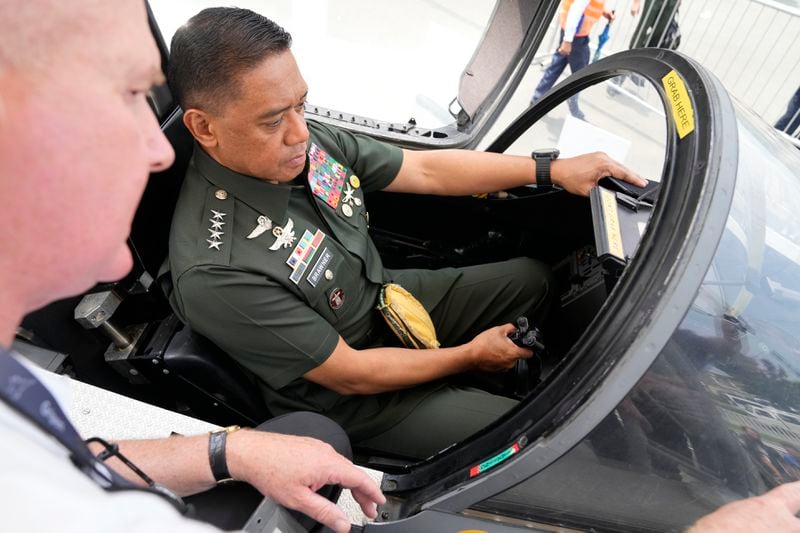 Philippine military chief Gen. Romeo Brawner Jr. right, sits inside the cockpit of a replica of a Saab Gripen combat aircraft during the Asian Defense and Security Exhibition on Wednesday, Sept. 25, 2024, in Manila, Philippines. (AP Photo/Aaron Favila)