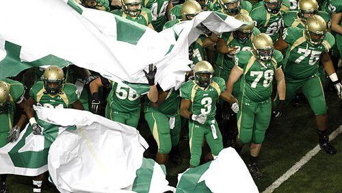 The Buford Wolves crash through a banner to announce their arrival.