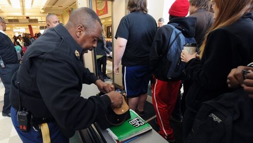 Master Sergeant Henry Bleach checks bags as students approach a metal detector at Grady High School on Thursday, March 7.