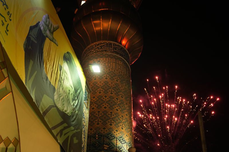 Fireworks explode next a portrait of slain Hezbollah leader Hassan Nasrallah and a minaret of a mosque in an anti-Israeli gathering celebrating Iran's missile strike against Israel, at Felestin (Palestine) Sq. in Tehran, Iran, Tuesday, Oct. 1, 2024. (AP Photo/Vahid Salemi)