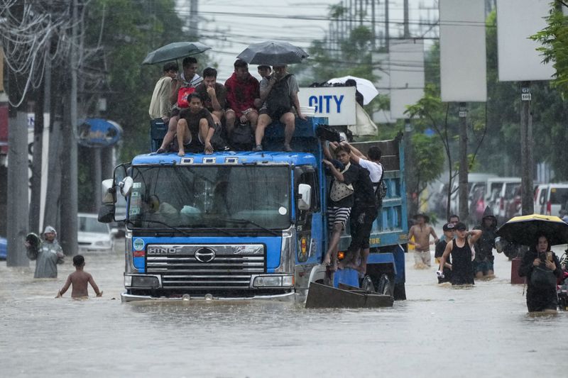 Commuters ride on top of a truck to avoid flood waters caused by heavy rains from Tropical Storm Yagi, locally called Enteng, on Monday, Sept. 2, 2024, in Cainta, Rizal province, Philippines. (AP Photo/Aaron Favila)