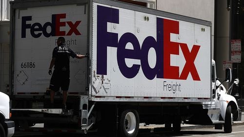 A FedEx worker closes the roll up door of a delivery truck.  FedEx, U.S. Postal Service and UPS each have ways customers can report and avoid email scams.