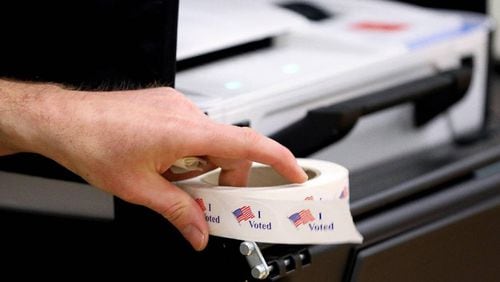 A precinct worker holds a roll of I Voted stickers next to a voting machine as voters cast their ballots at Clays Mill Elementary School on May 16, 2023, as Kentucky went the polls on primary election day. Workers at this precinct said they had 40 people vote in the first two hours the polls were open.