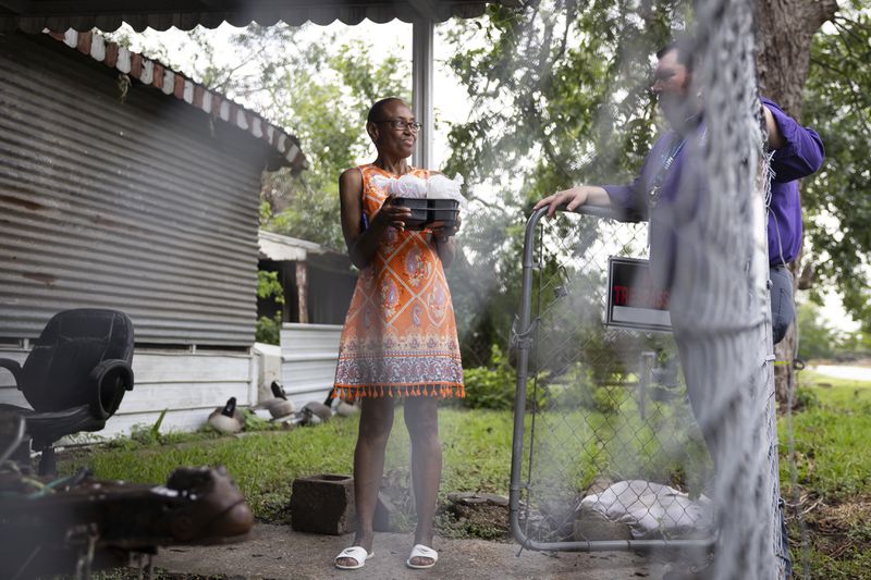 Meals on Wheels client Annie Jones chats for a moment after receiving a food delivery from Meals on Wheels Director of Operations Matthew Wright, Friday, July 12, 2024, in Houston. Deliveries include a hot meal and cold drink but also human connection and a welfare check. (AP Photo/Annie Mulligan)